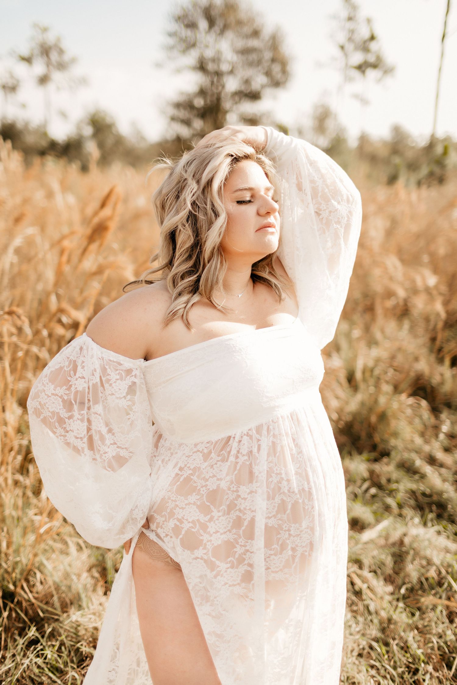 a pregnant mom is ruffling her hair with her eyes closed while posing for a photo