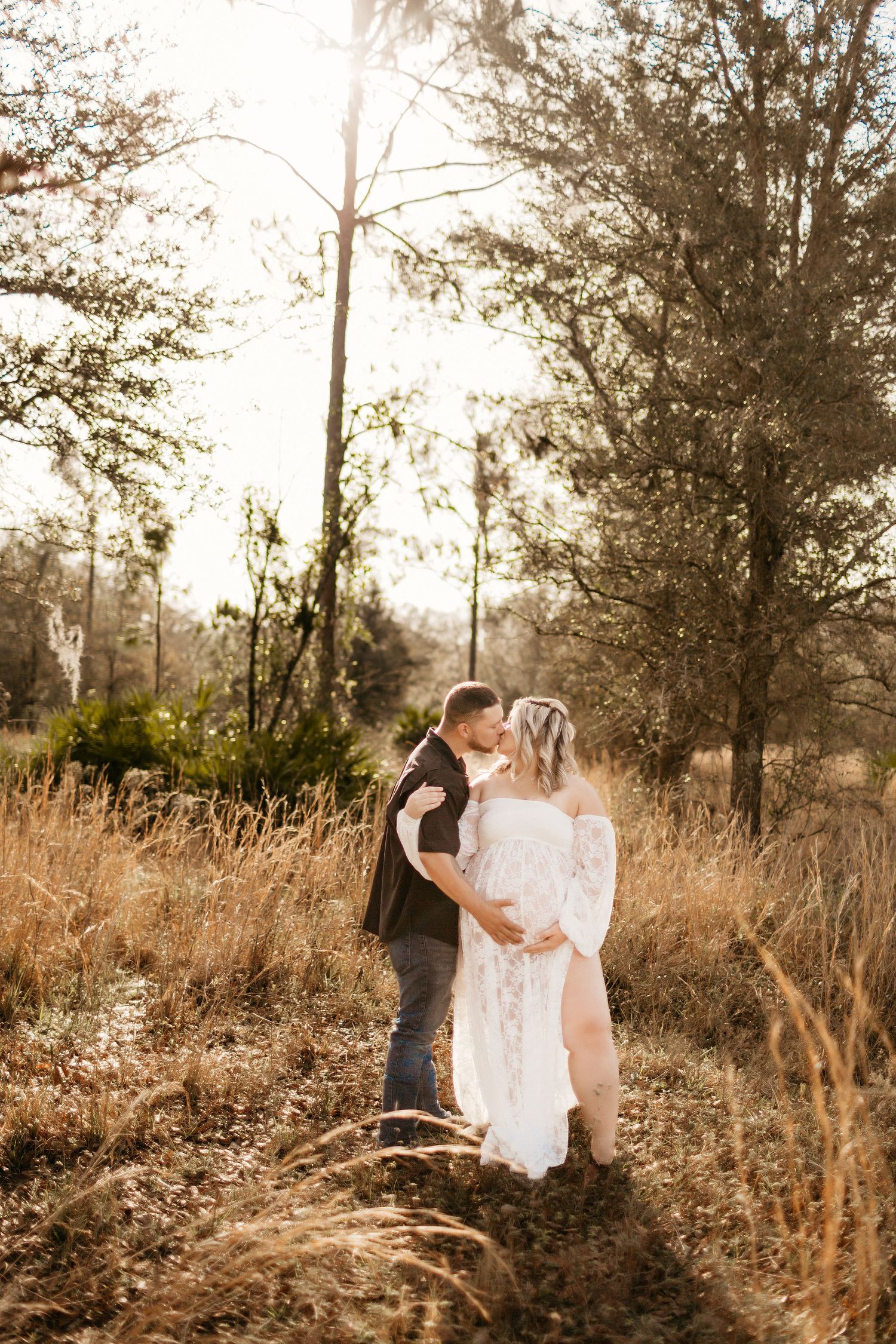 a pregnant mom and her spouse are holding her belly with eyes closed while posing for a photo
