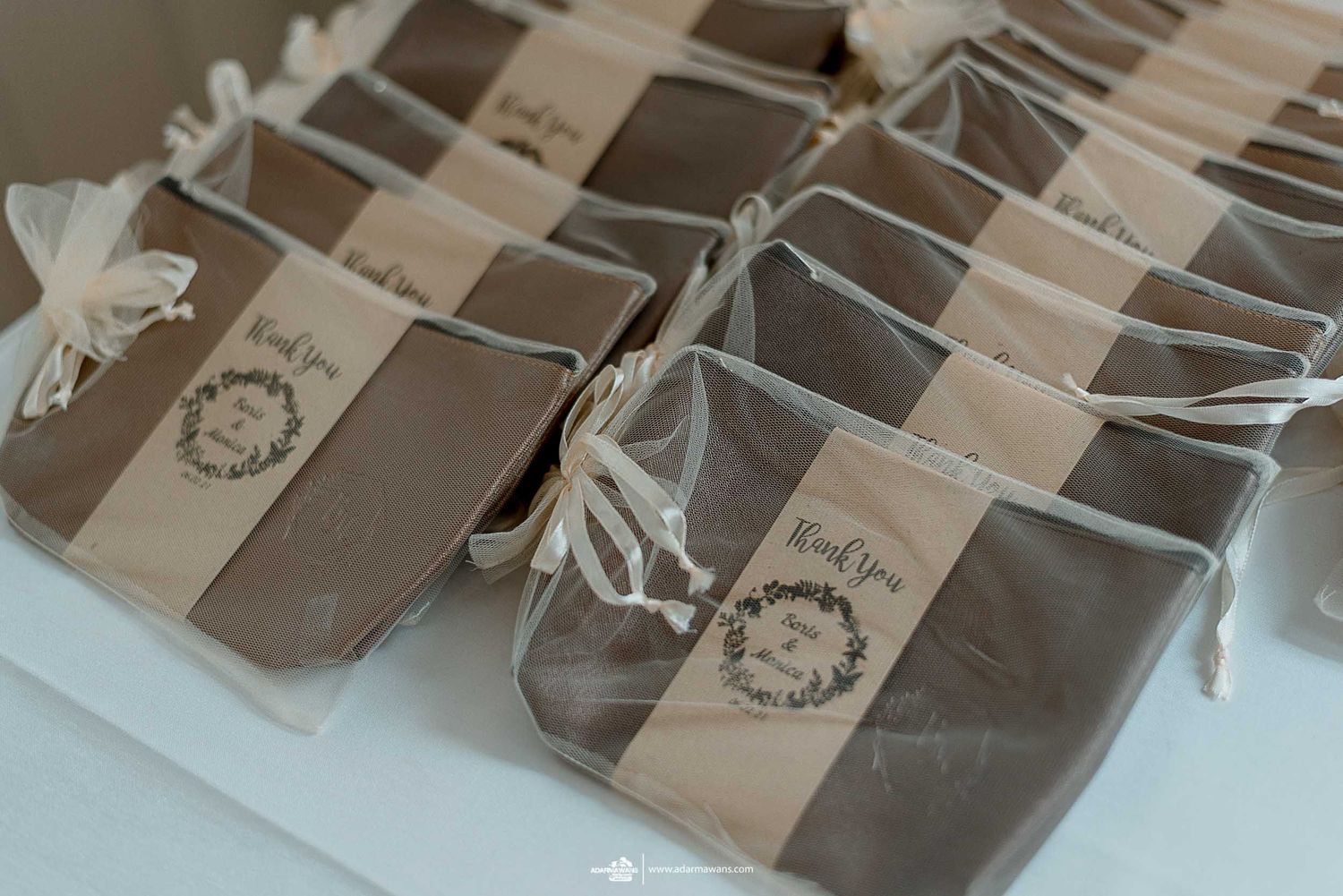 Brown wedding favor bags with custom labels arranged neatly in rows.