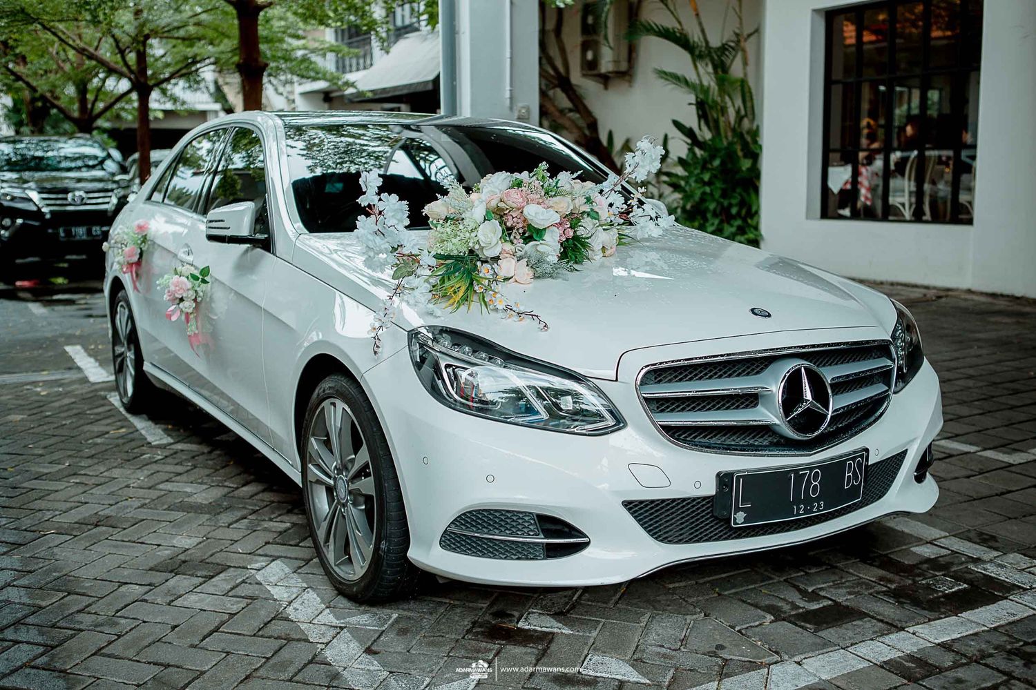 White Mercedes-Benz decorated with delicate floral arrangements for a wedding.
