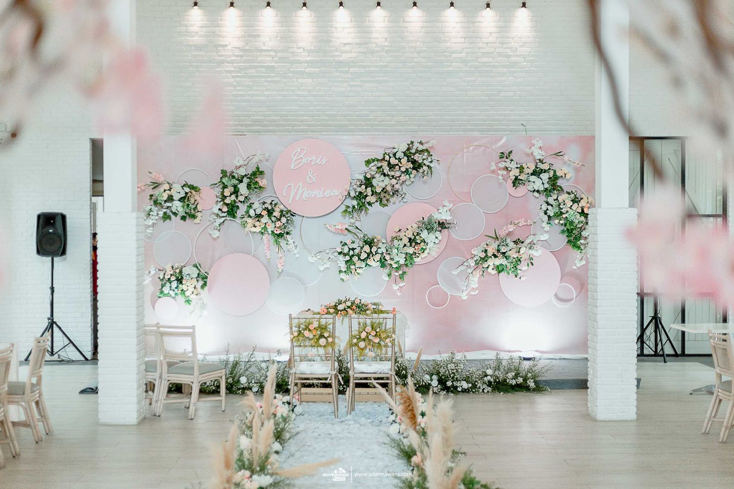 Modern wedding venue decorated with suspended floral arrangements and pink accents.