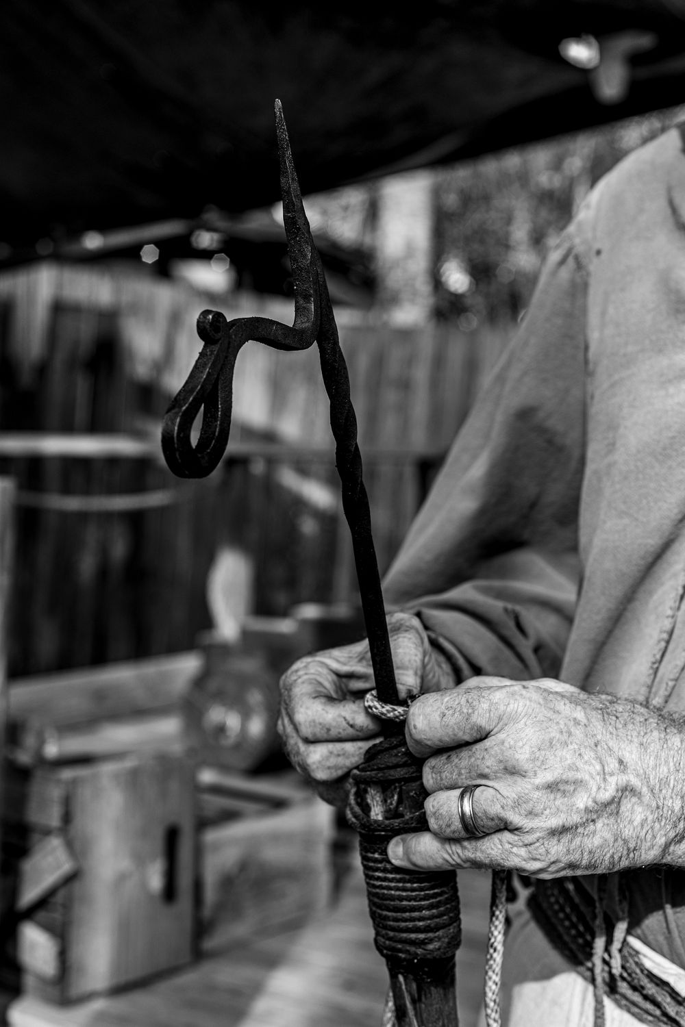 Craftsperson holding antique tool in workshop, detailed black and white shot.