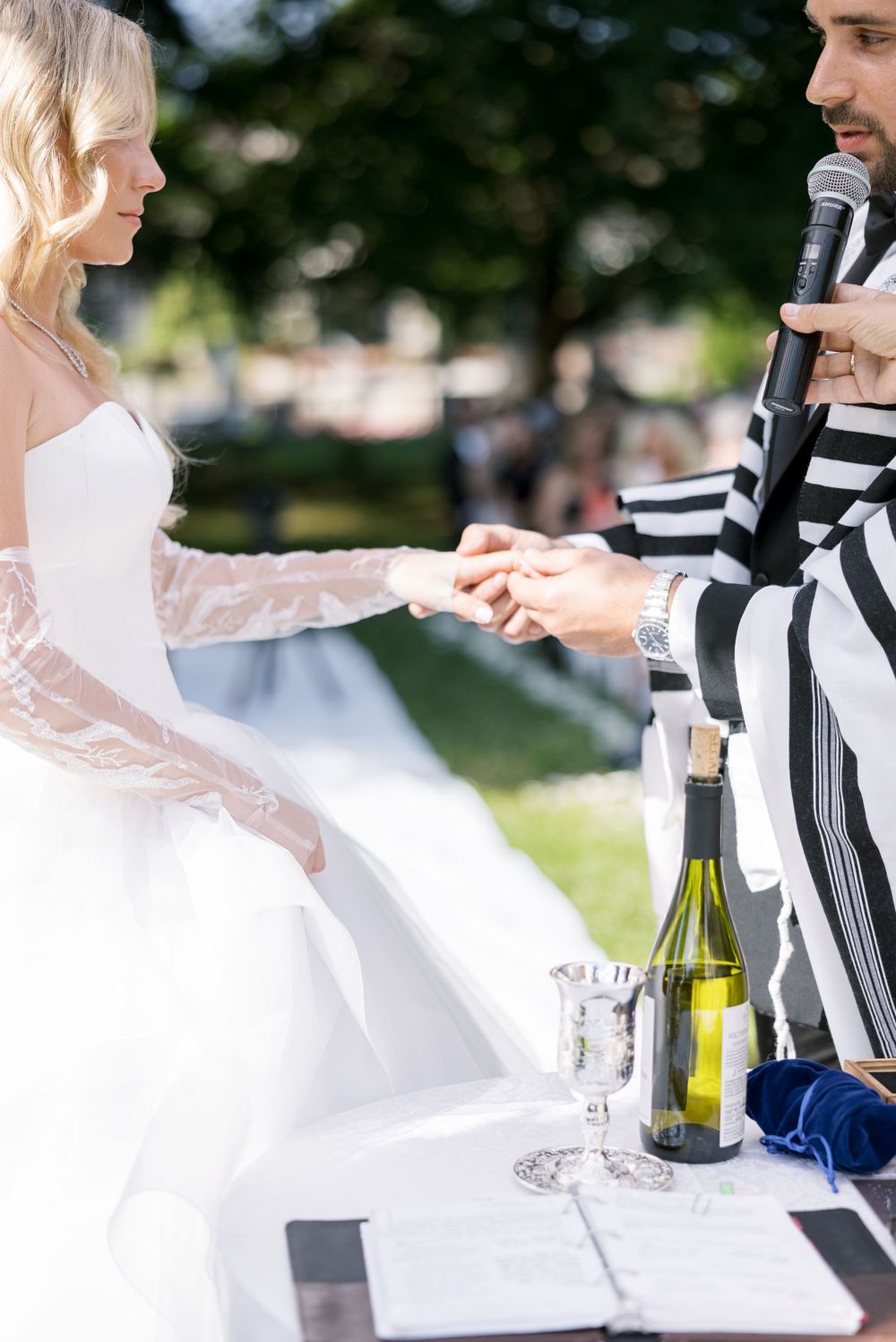 Wedding ceremony scene with white decor and wine bottles on outdoor table.