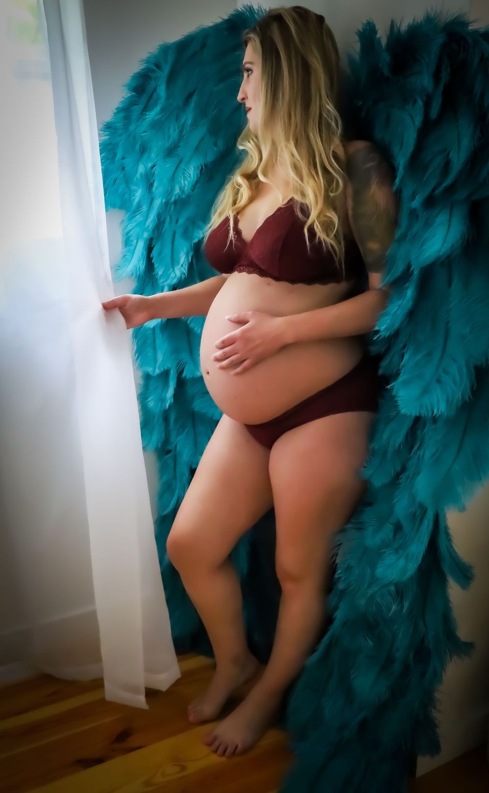 Artistic portrait with teal feathered wings and burgundy accents.