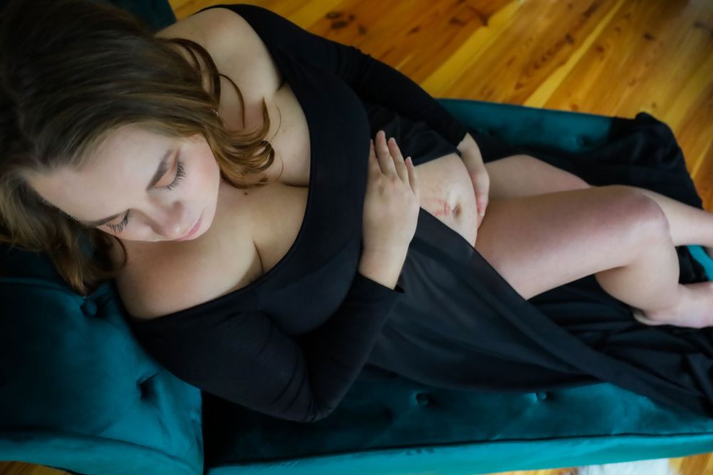 Woman in black clothing reclining on teal colored bedding.
