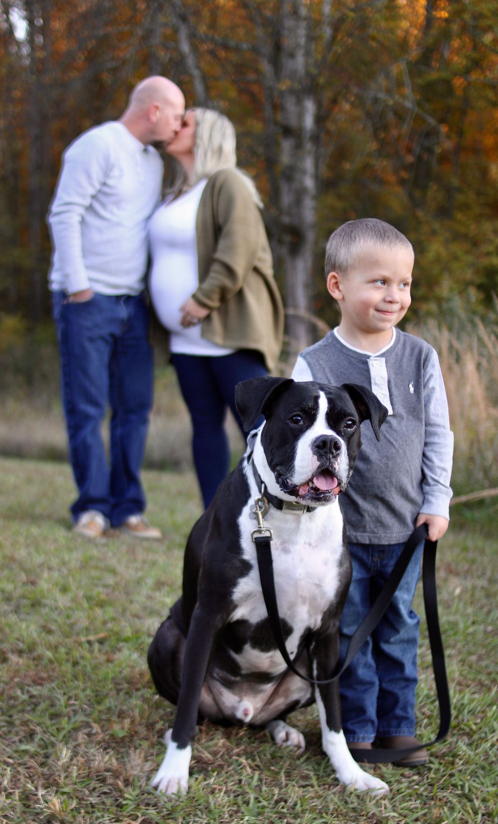 Child and black and white dog posing together during autumn family photoshoot.