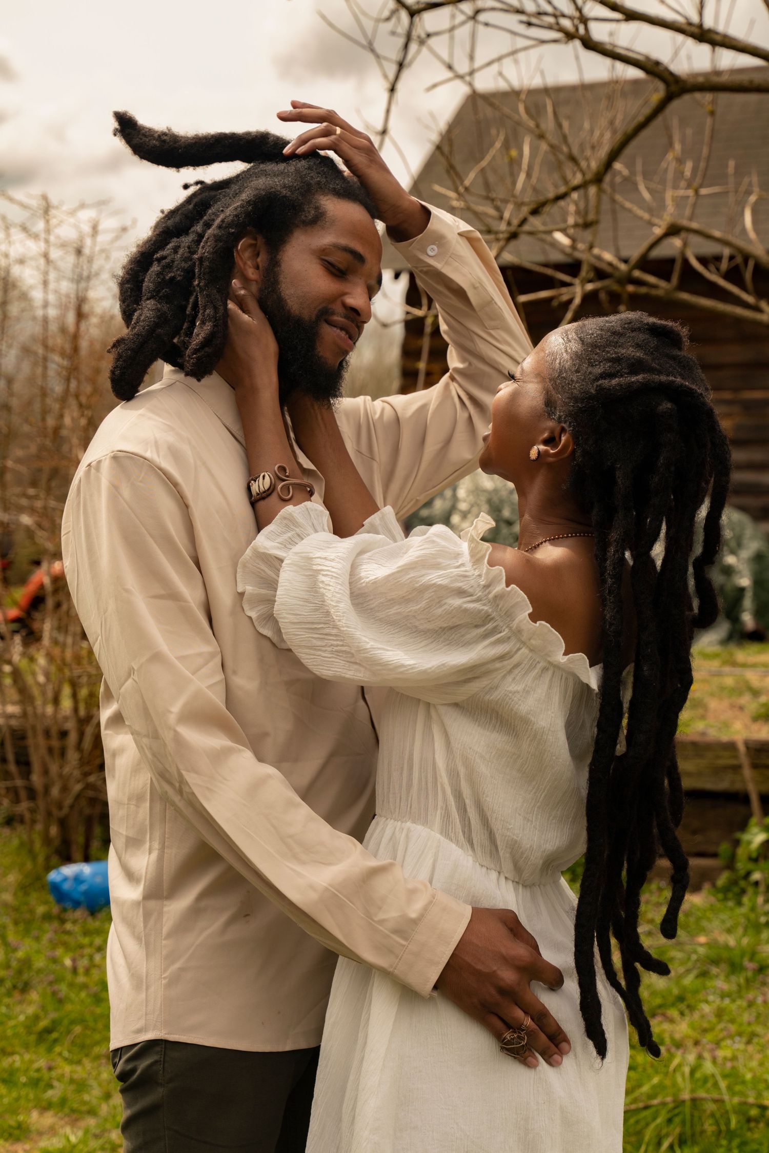 A romantic moment captured between two people in light colored clothing against a natural backdrop.
