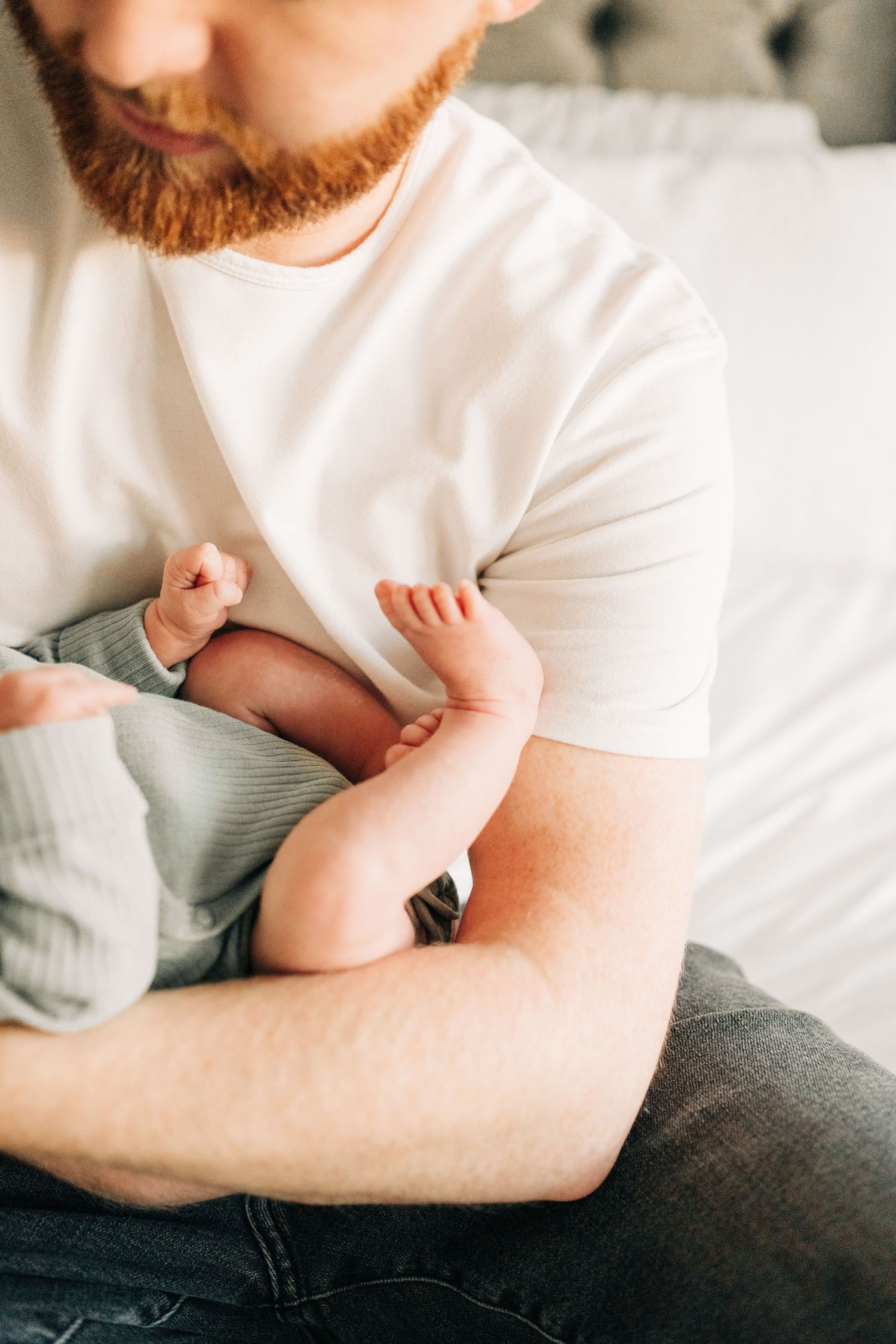 dad holding newborn on bed for a lifestyle newborn session in Dallas, TX