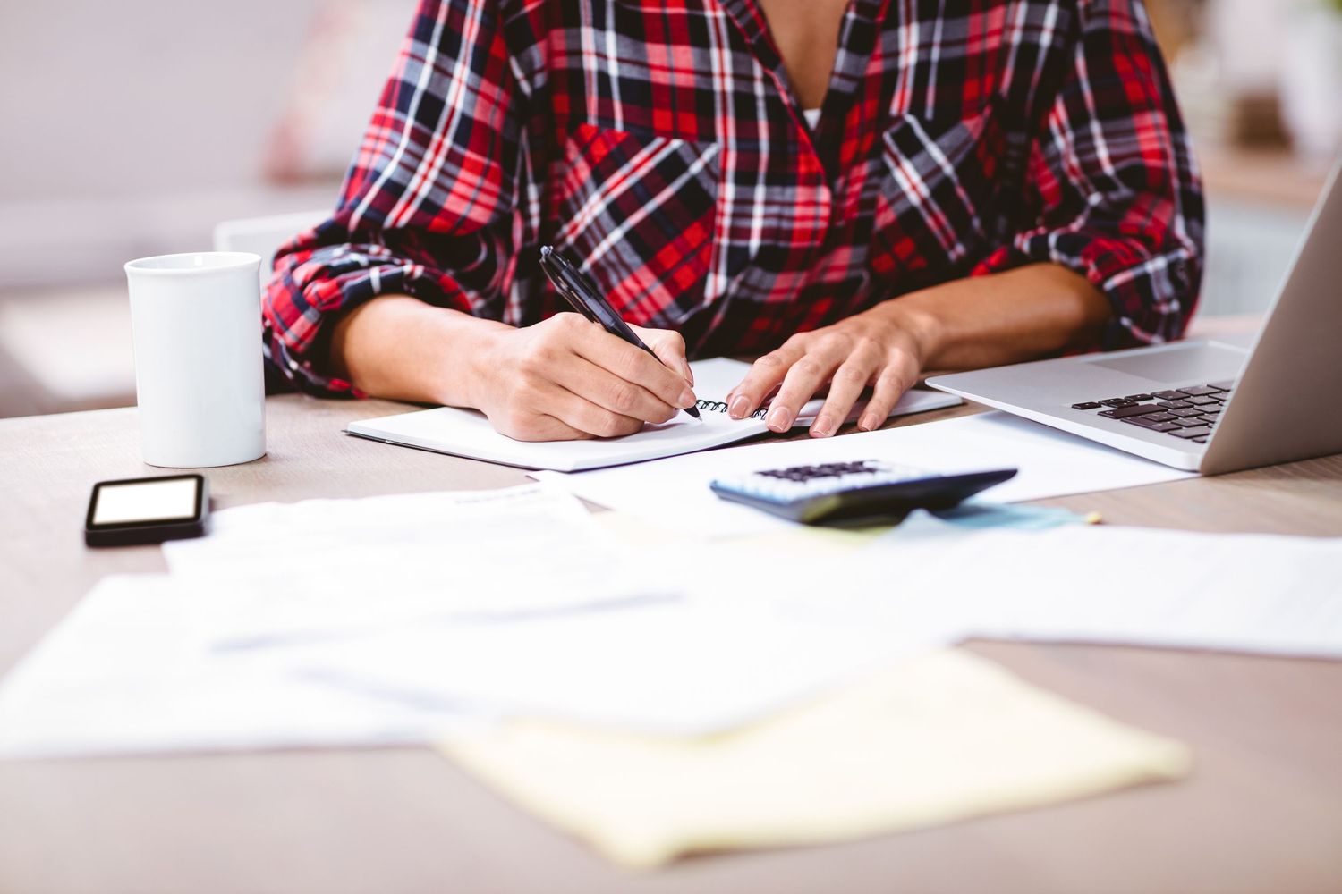 woman writing notes in front of laptop