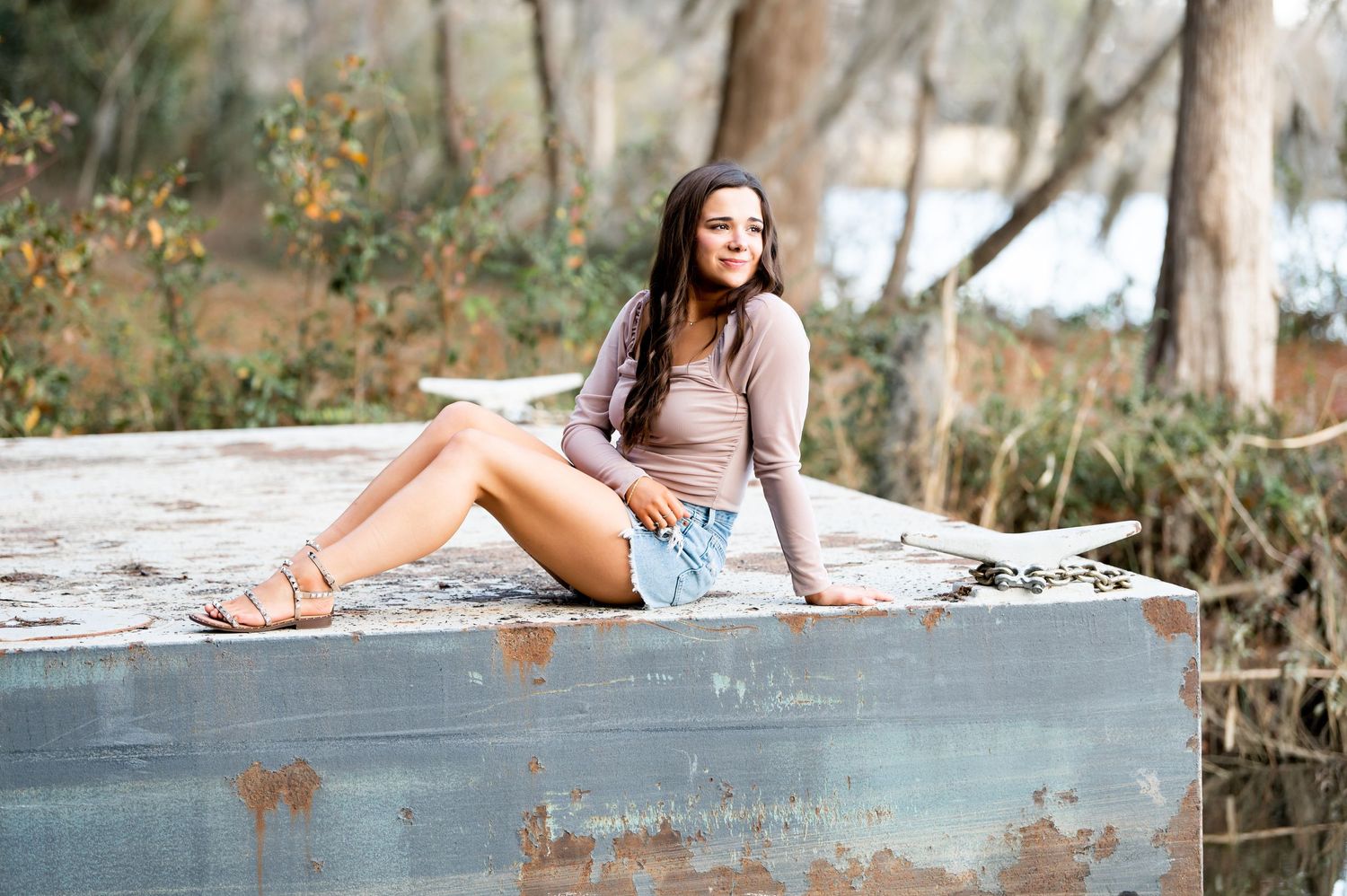 Artistic portrait session on a rustic concrete ledge in an outdoor setting.