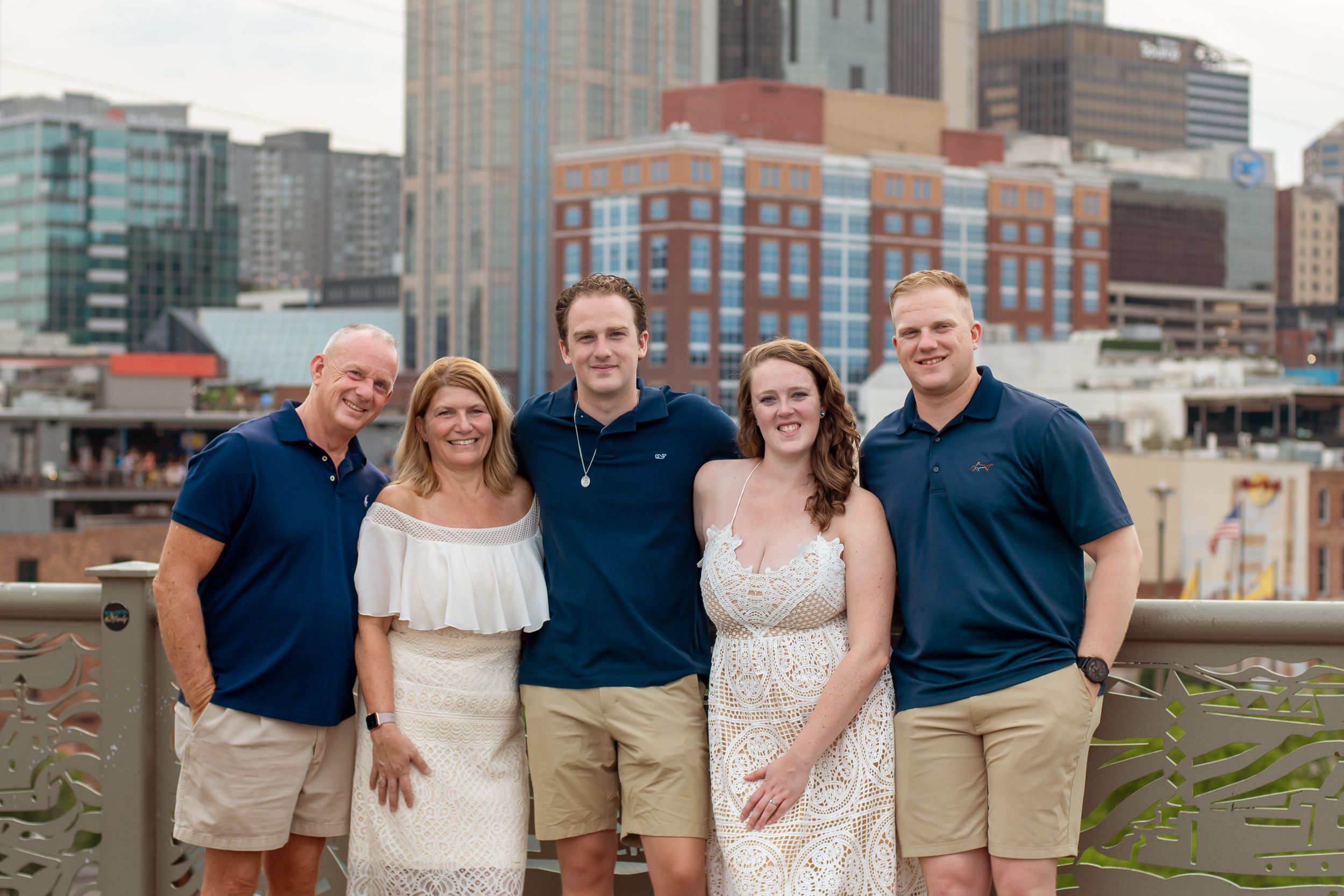 Family group photos against modern city skyline wearing coordinated casual outfits.
