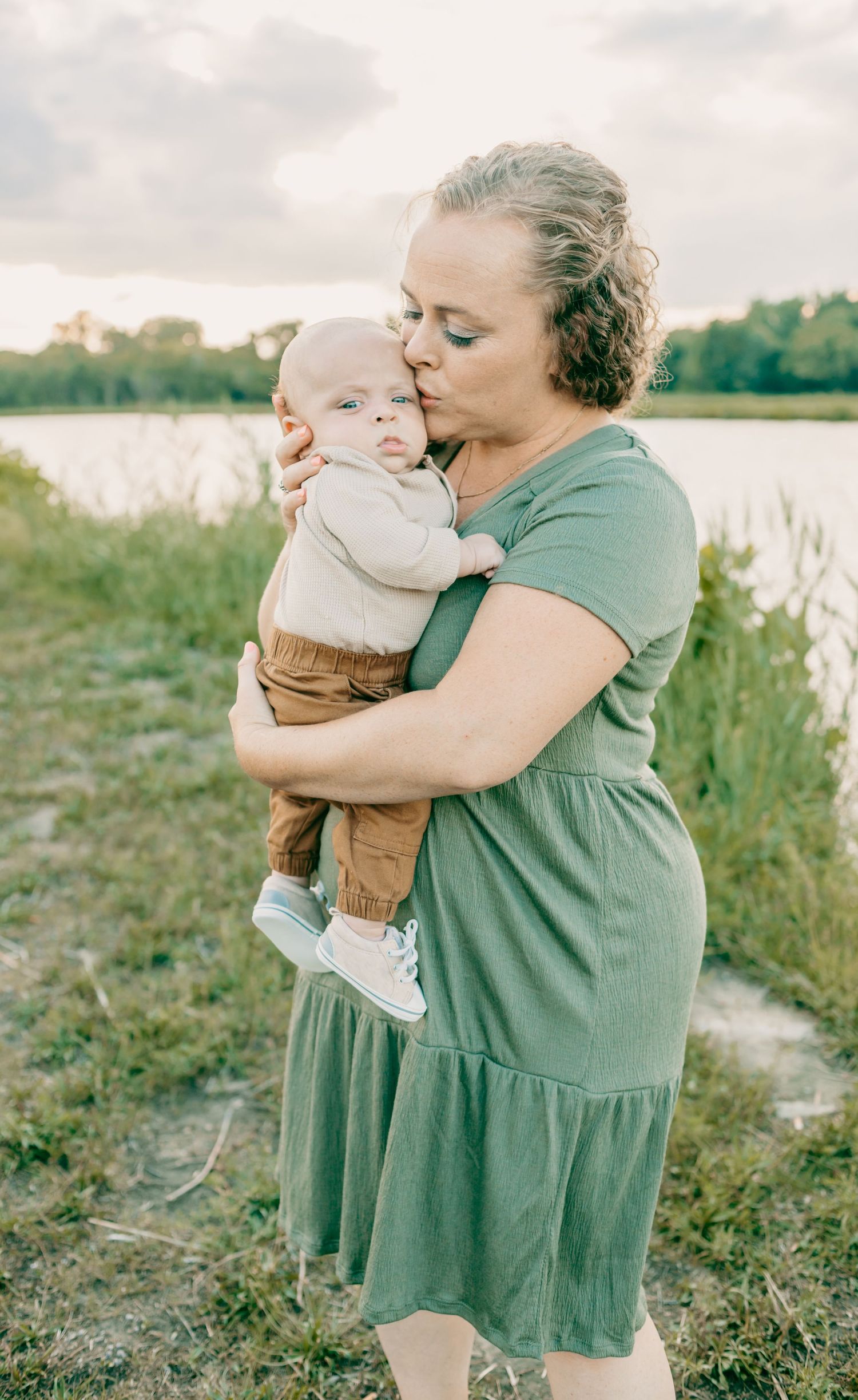 Gentle embrace between adult and infant against natural outdoor backdrop.