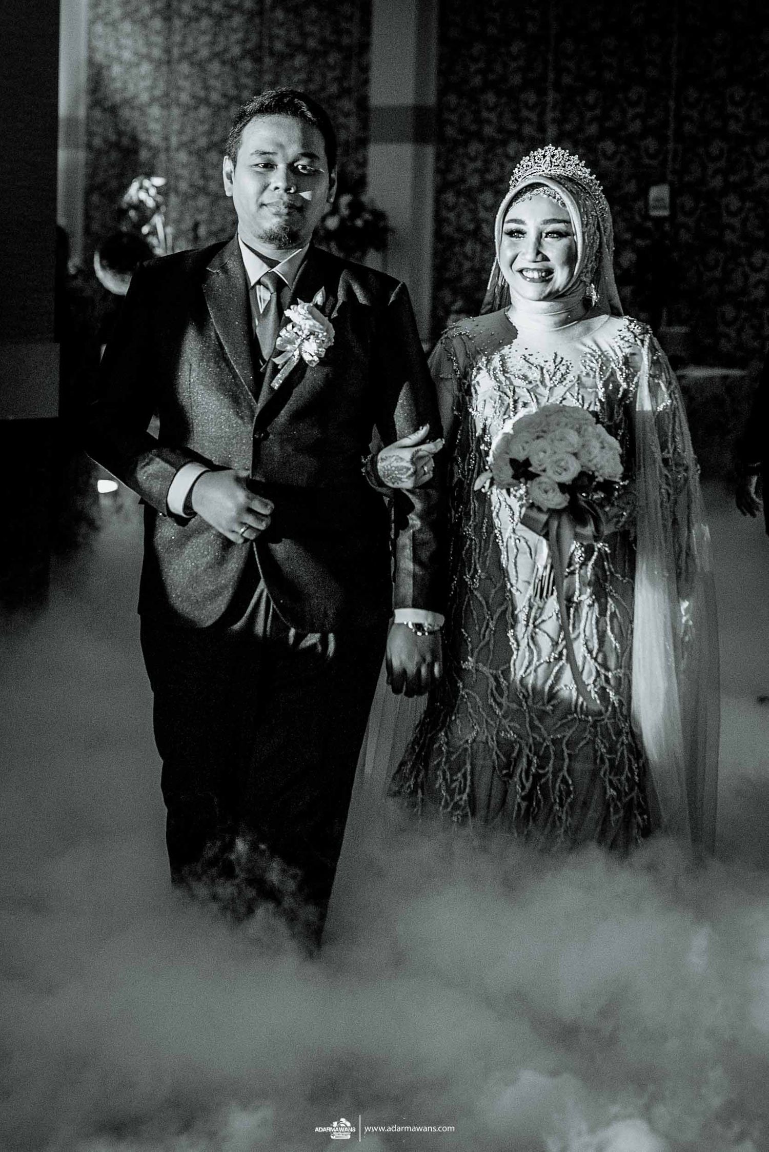 A dramatic black and white wedding portrait with atmospheric fog effects on the dance floor.