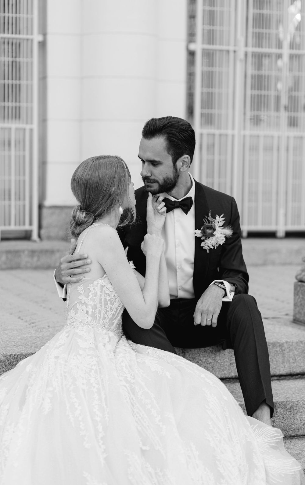 A black and white intimate portrait of newlyweds seated on stone steps.