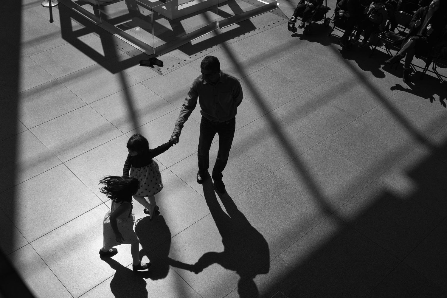 Daniel Bowler's award winning family photography. A candid black and white shot of a father dancing with two daughters.