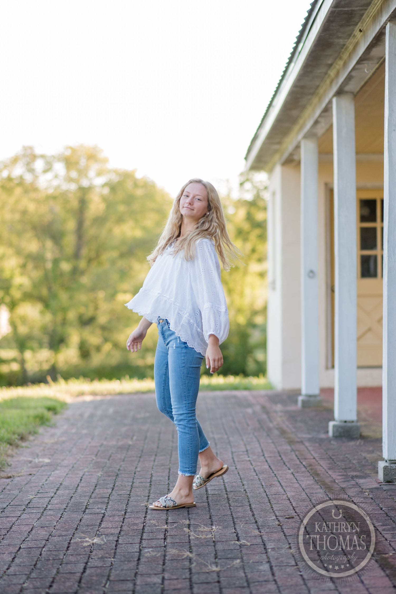 Candid lifestyle photo on brick pavement featuring bohemian white blouse and skinny jeans.