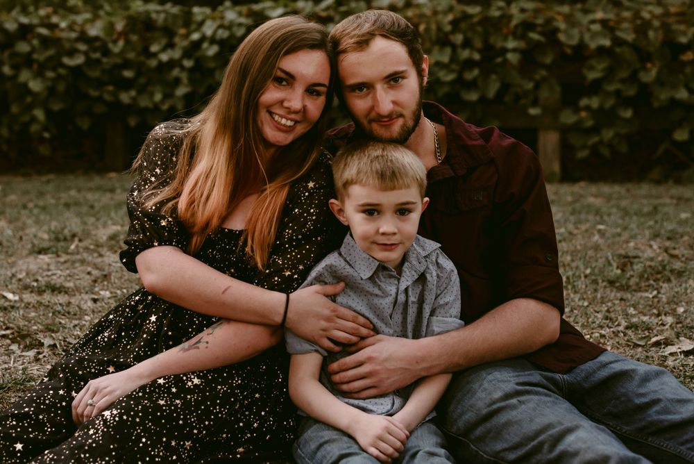 A family sits together for a casual portrait outdoors during autumn.