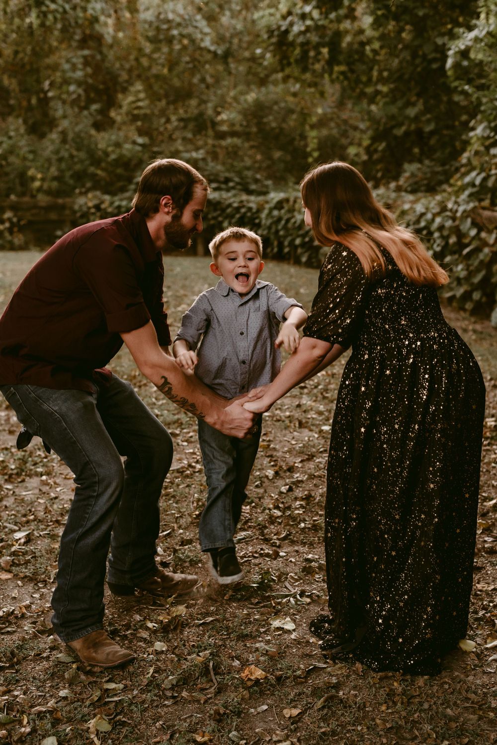 Parents swing their excited child between them while playing outdoors.