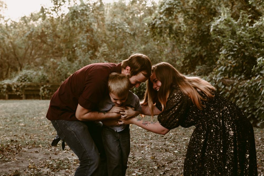A family shares a joyful moment while playing together in a wooded setting.