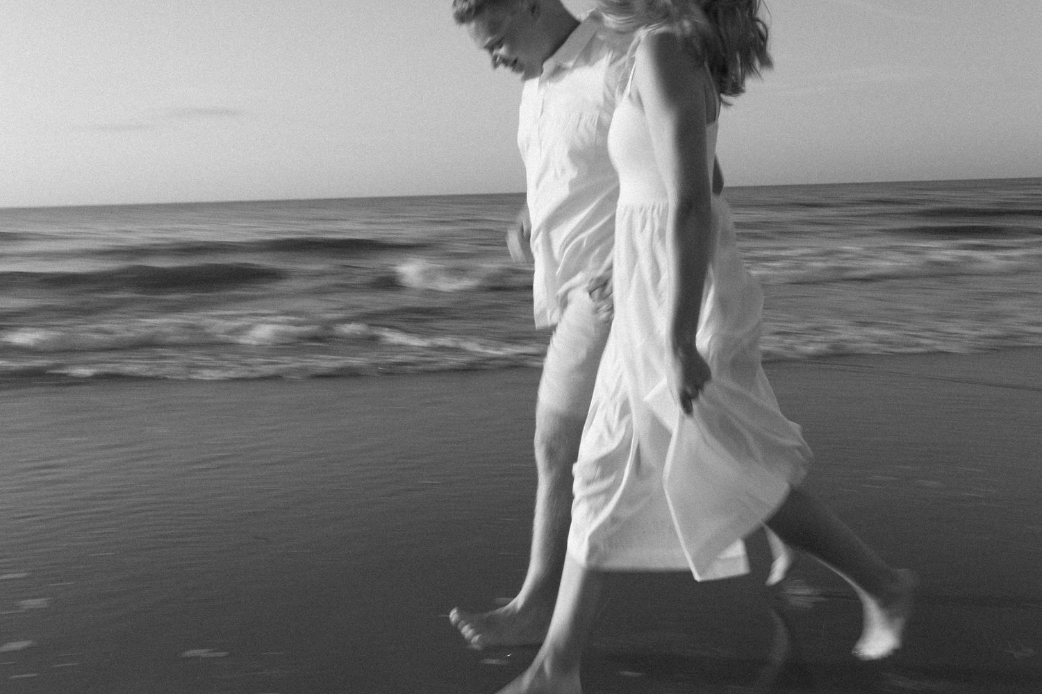 Black and white photo by B. Logsdon of a couple running along the beach on Hilton Head Island, South Carolina.