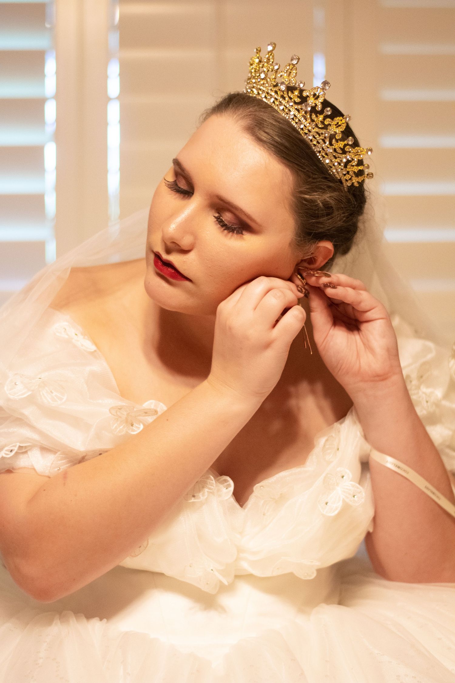 Elegant bridal portrait with gold crown and delicate veil.