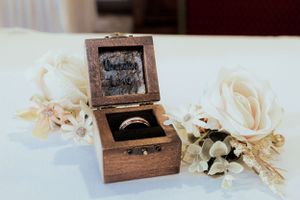 A rustic wooden ring box with white roses and dried flowers for a wedding ceremony.