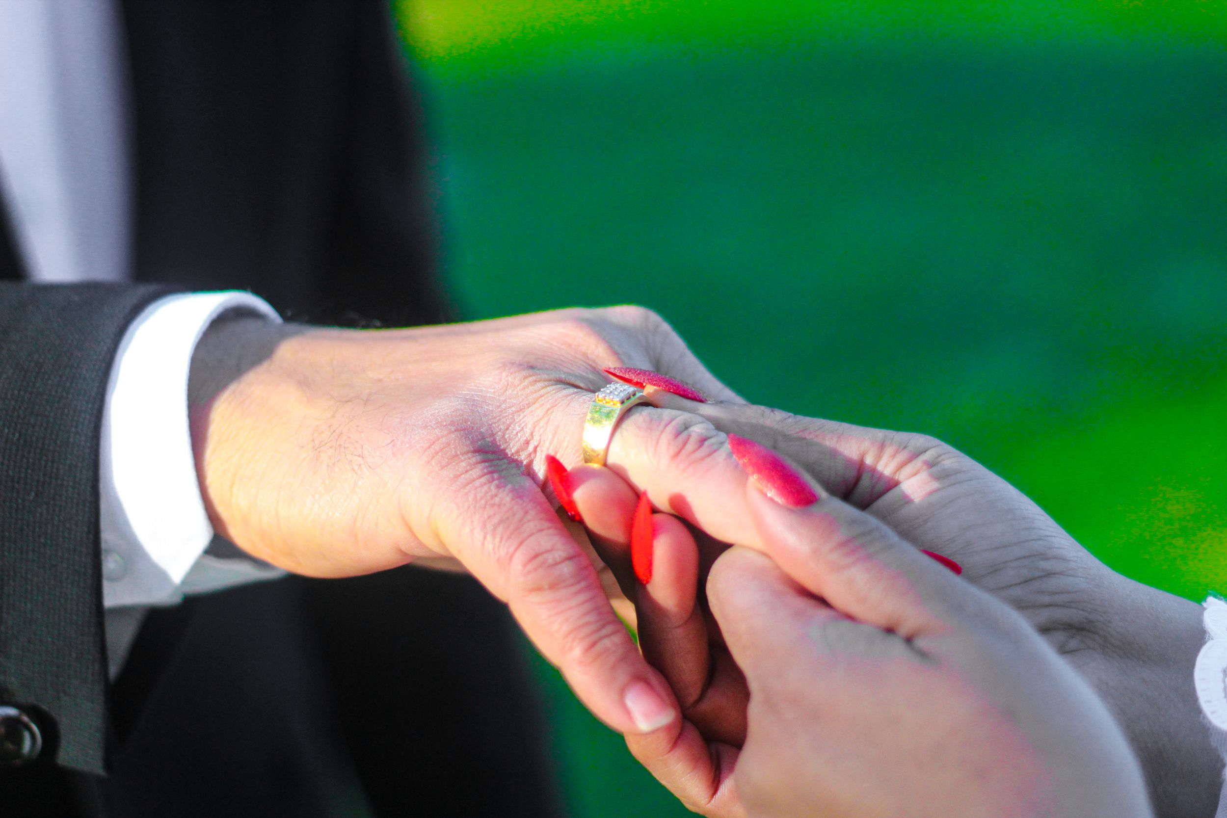 Close up shot of hands exchanging wedding rings during a ceremony.