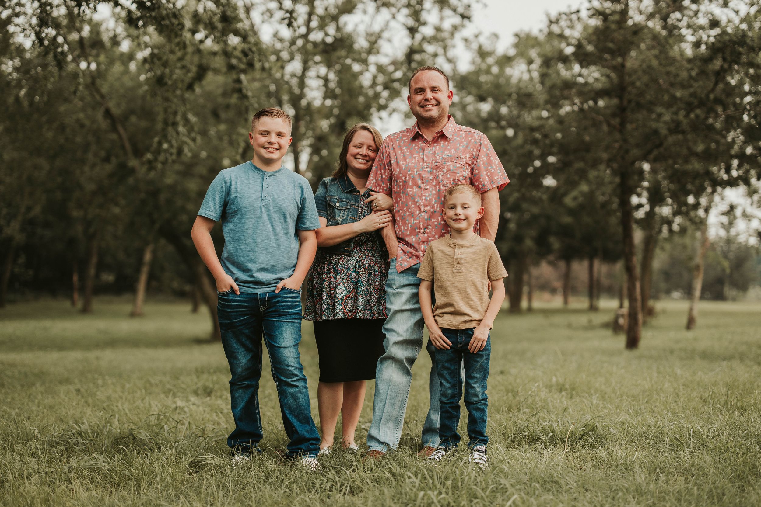 Family portrait session in a park with natural lighting and trees in background.