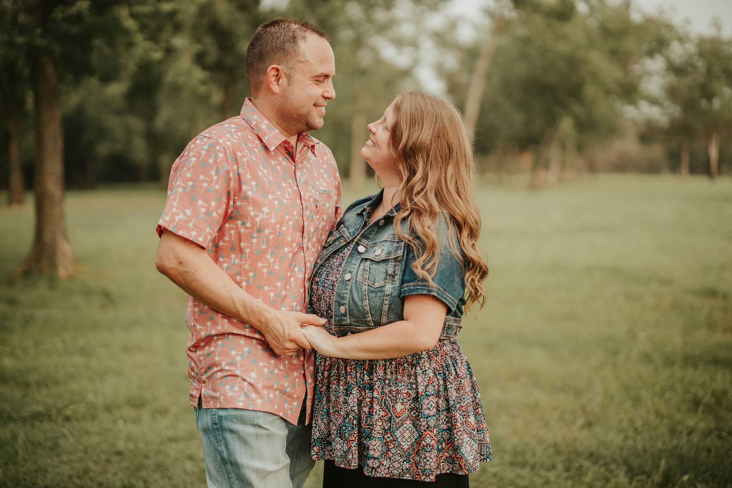Couple embracing in a casual photoshoot outdoors in a grassy field.