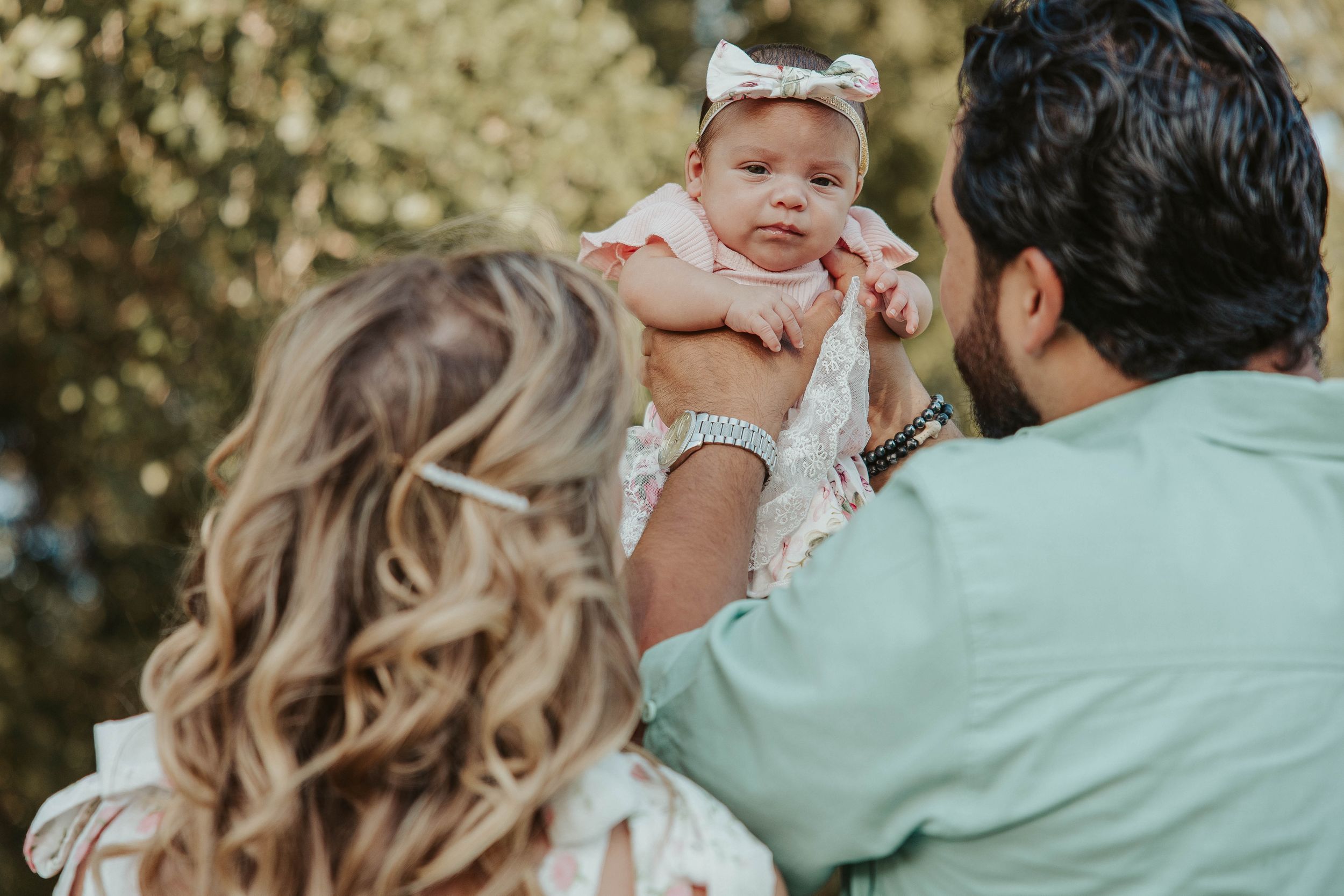 A sweet moment with a baby being held up during an outdoor family photoshoot.