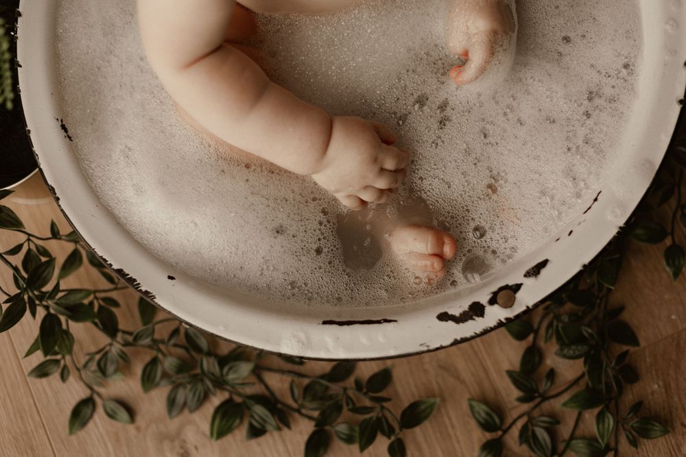 Small feet in a white vintage style bowl with greenery decorations.