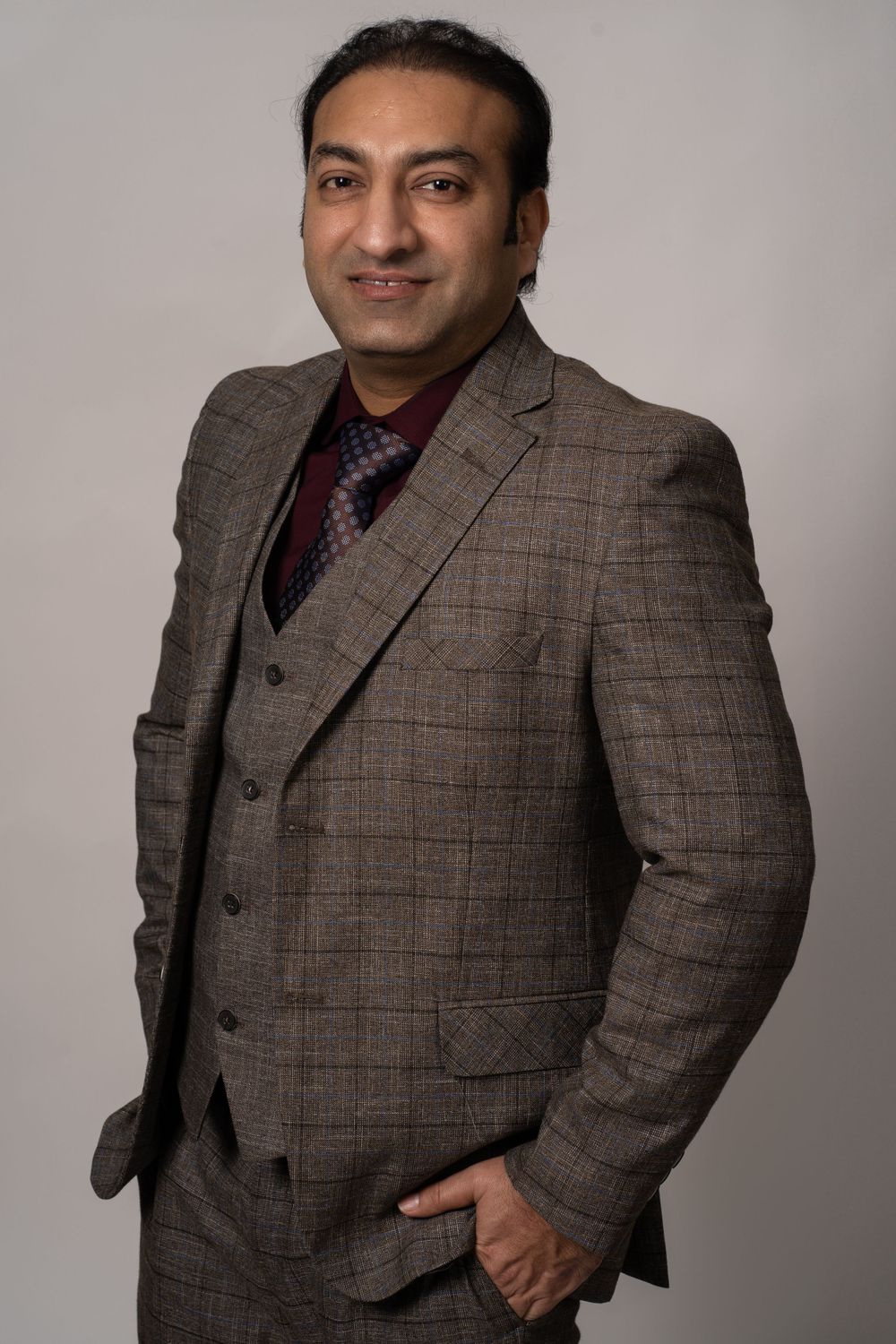 Formal portrait of man wearing checkered brown suit and tie.