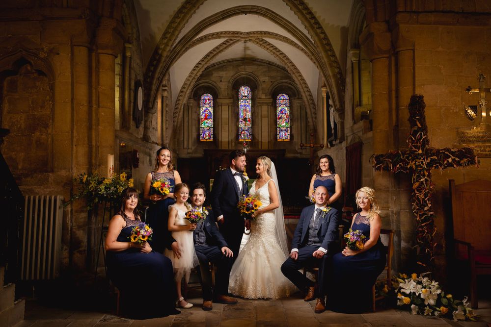 Gothic church interior with arched stone ceilings and stained glass windows during wedding ceremony.