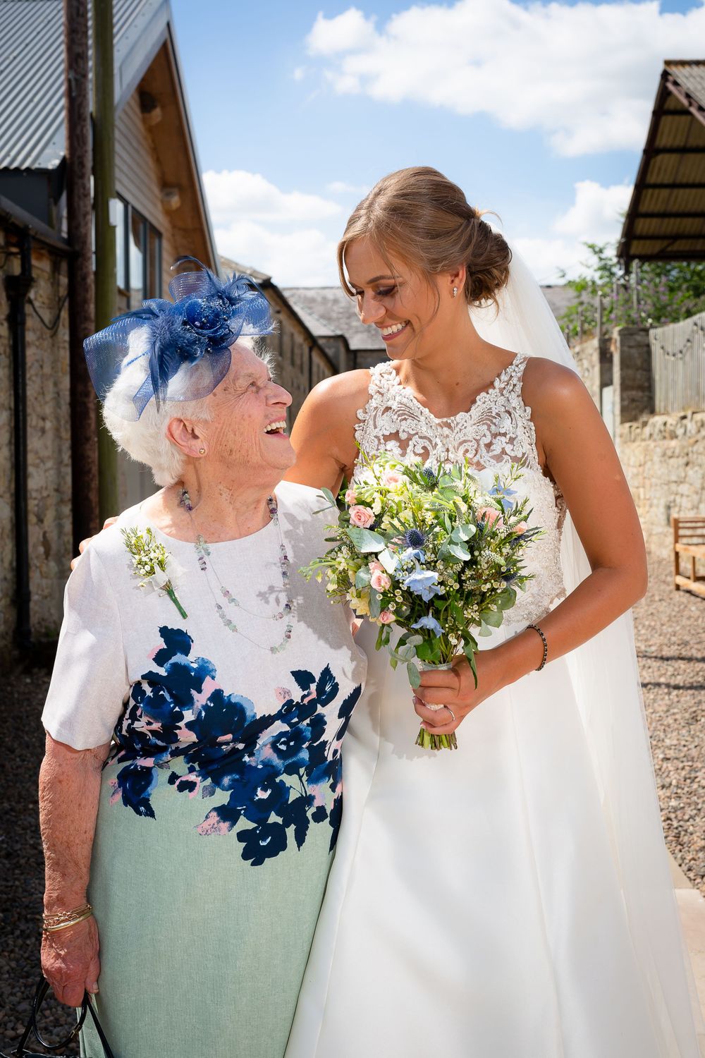 Candid outdoor wedding moments with floral bouquets against stone wall backdrop.