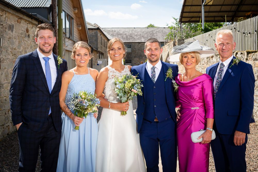 Wedding party members pose together in formal attire with light blue and magenta accent colors.