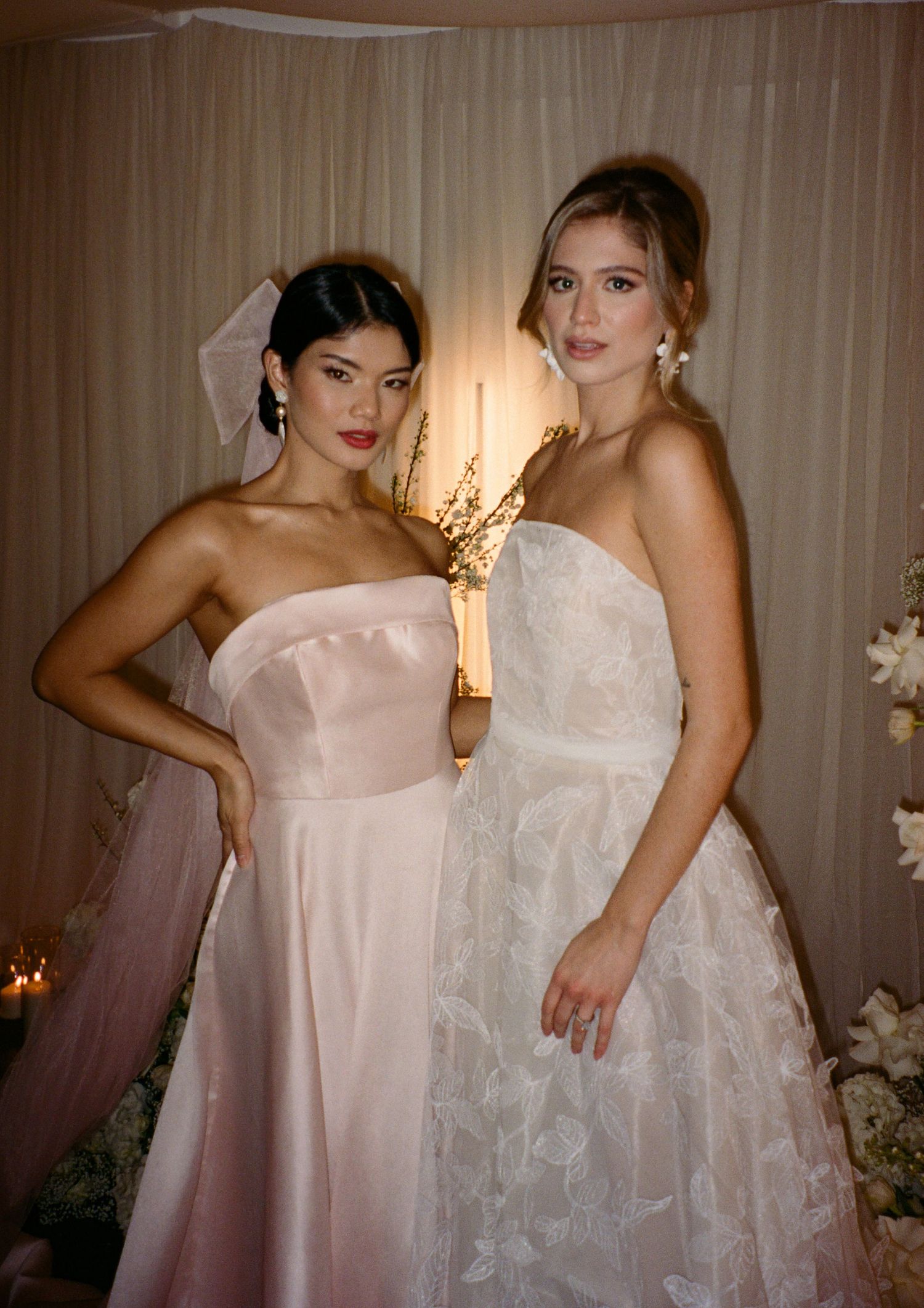 Two elegant women in formal gowns posing at glamorous evening event.