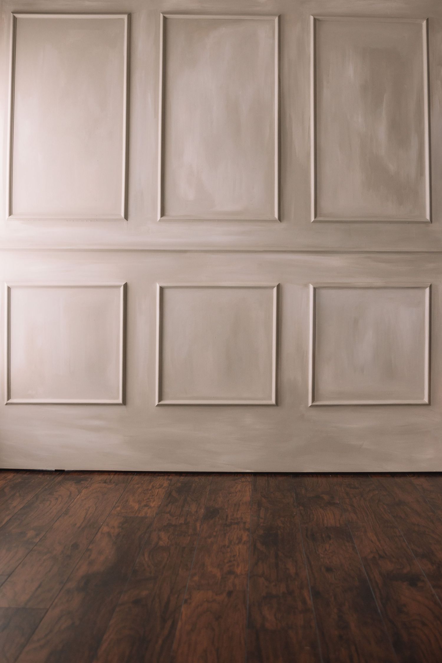 Minimalist interior with beige paneled wall and dark hardwood flooring.