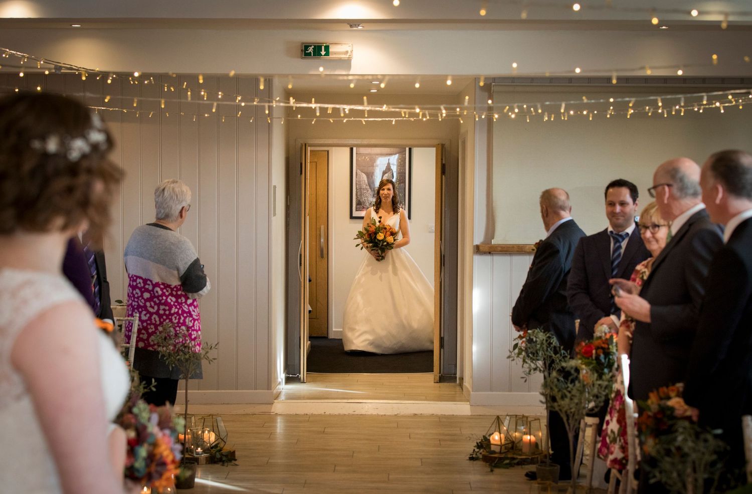 Wedding reception hall decorated with string lights and floral arrangements.