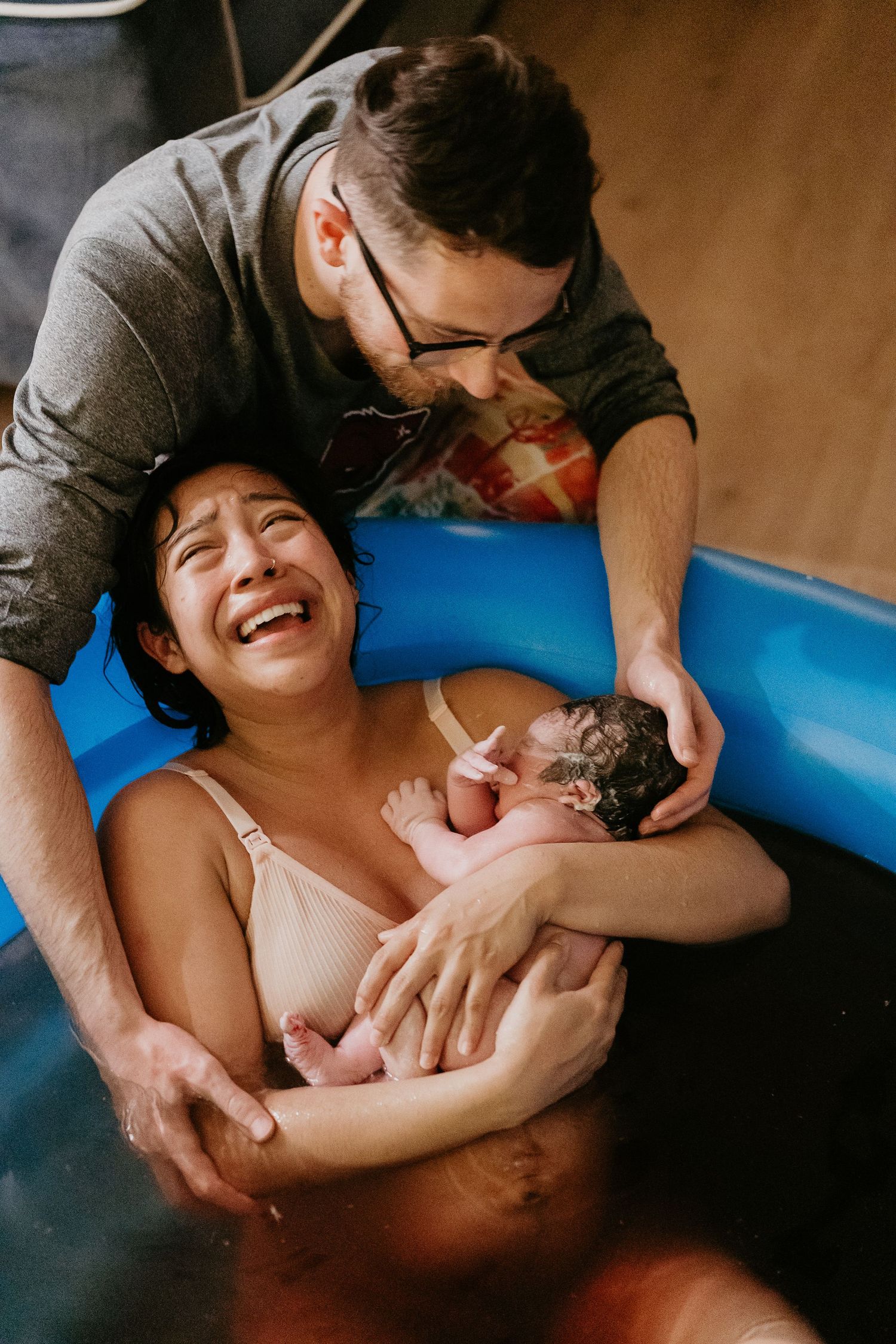 mom cries with happiness holding baby. mom cries after at home natural waterbirth