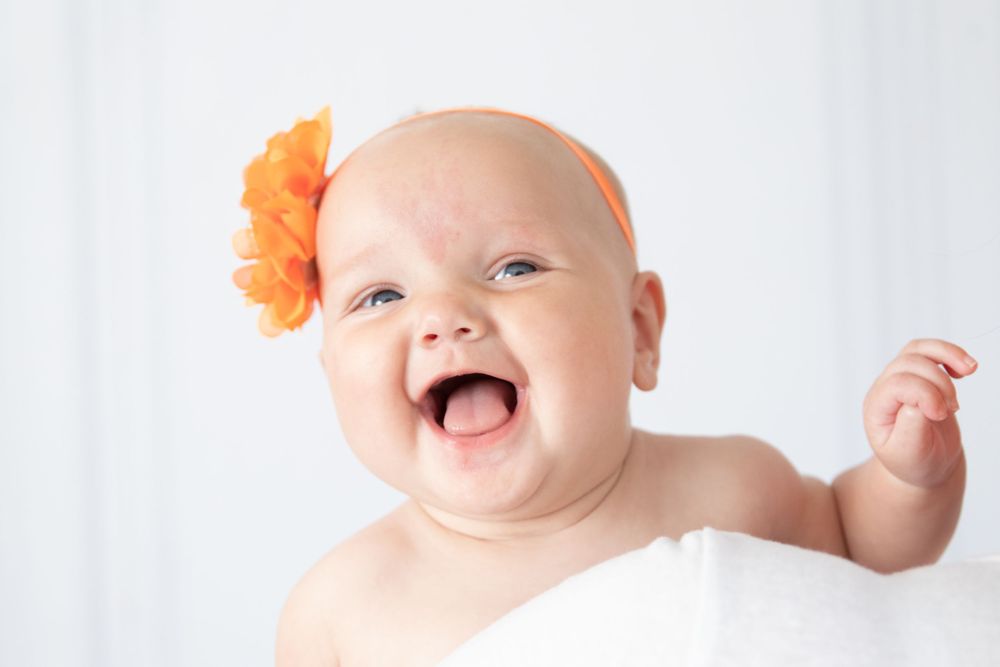 baby girl laughing with yellow flower headband