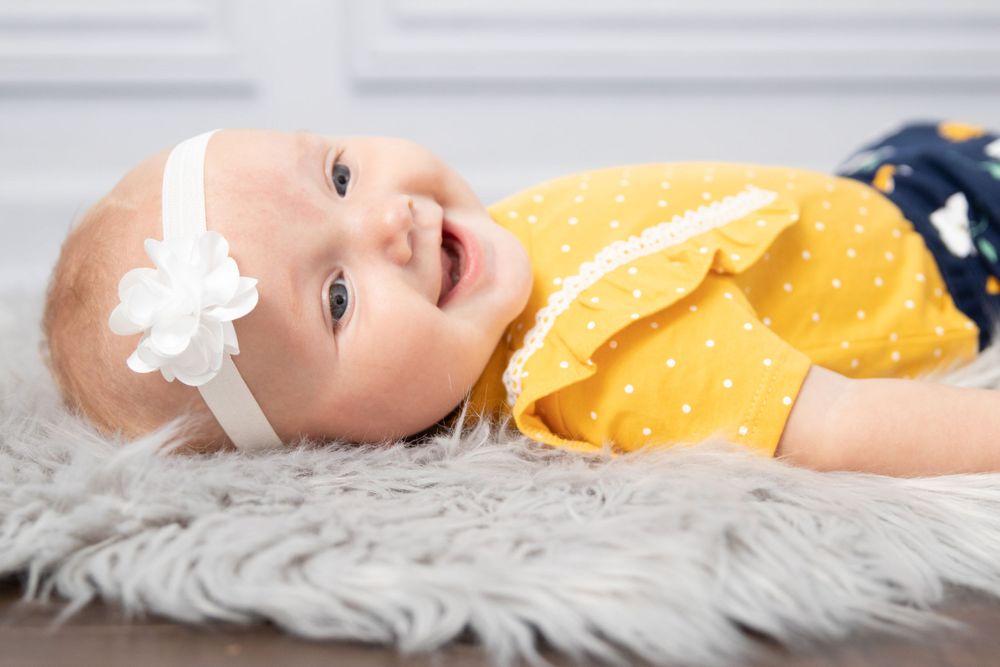 baby girl yellow shirt white headband laughing