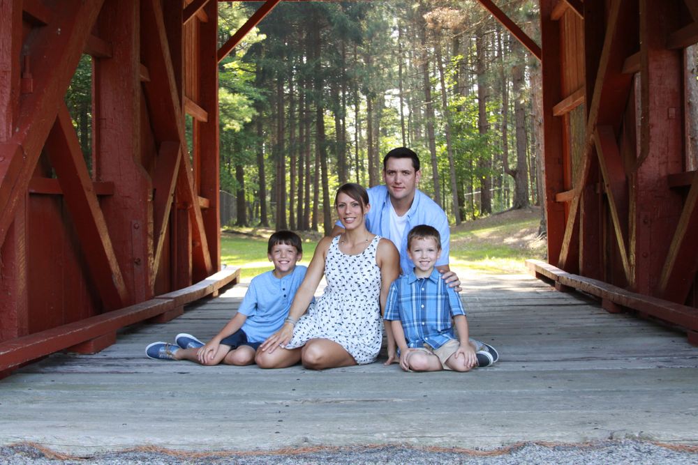 family of 4 at rustic covered bridge