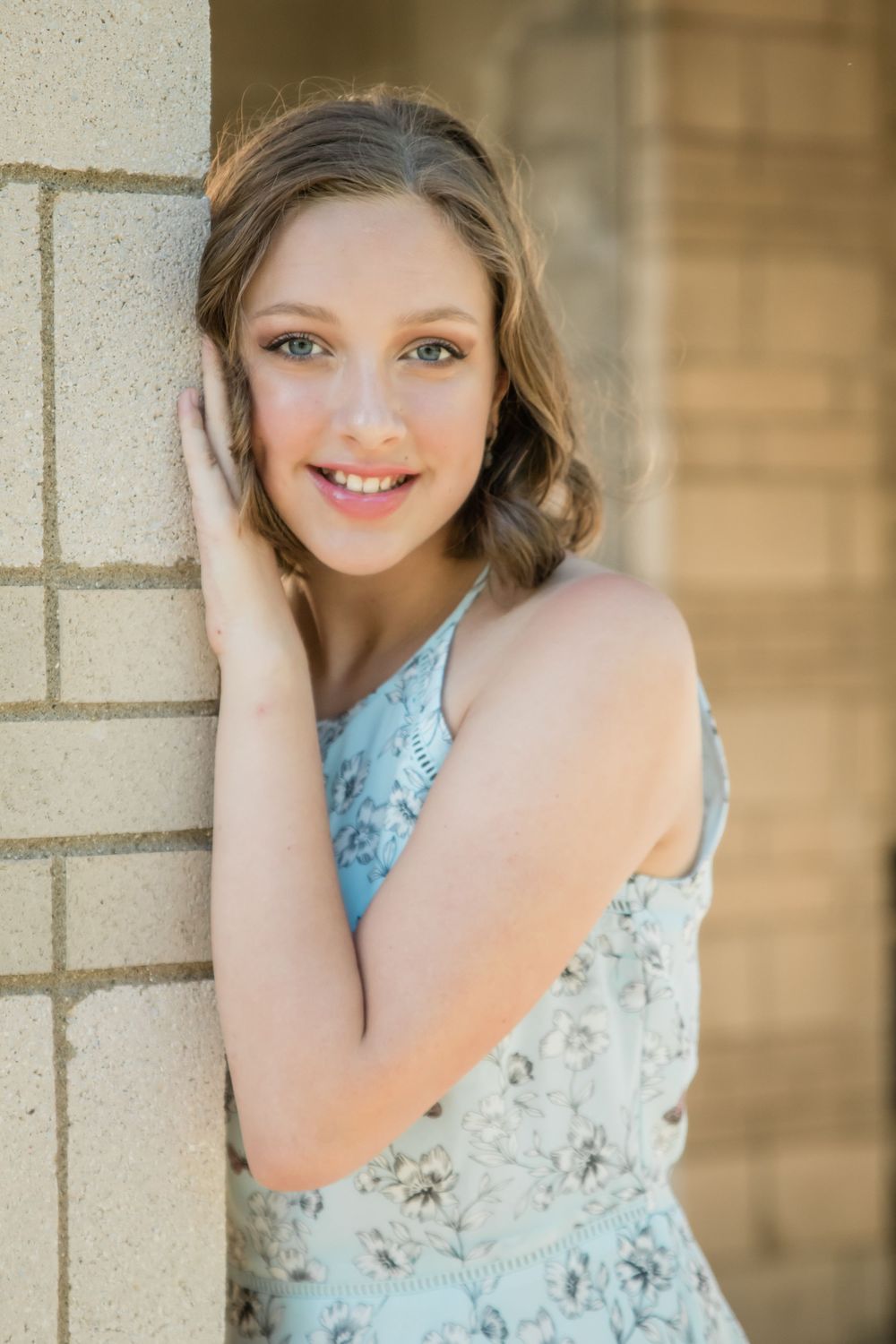 girl leaning on brick pillar