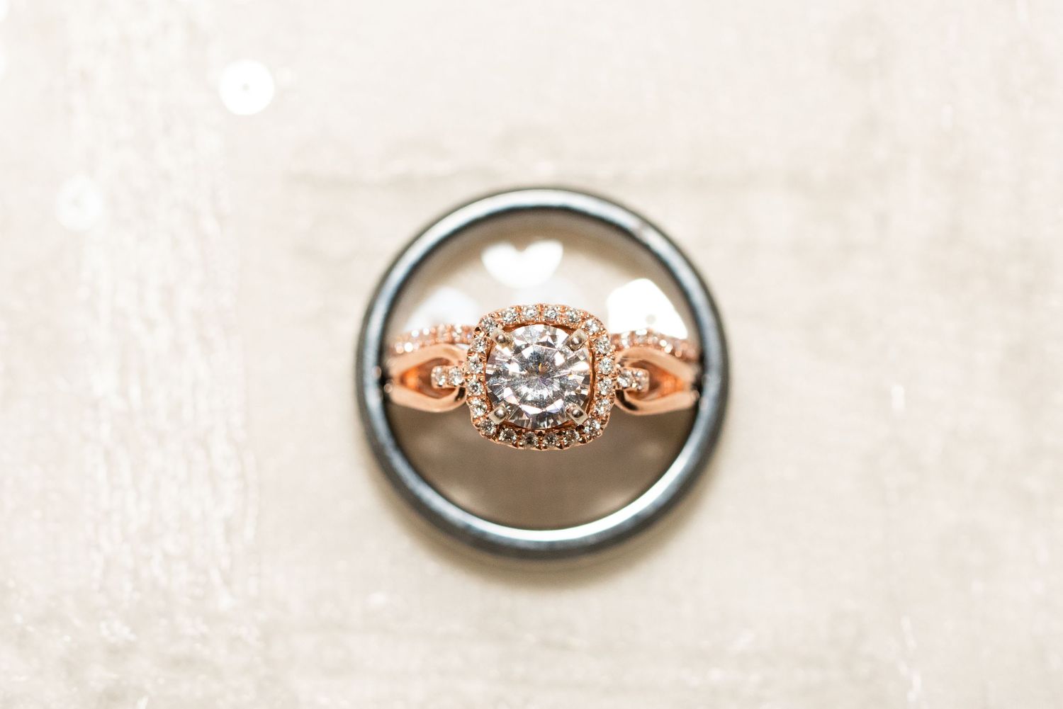 A rose gold engagement ring with diamond details photographed through a wedding band.