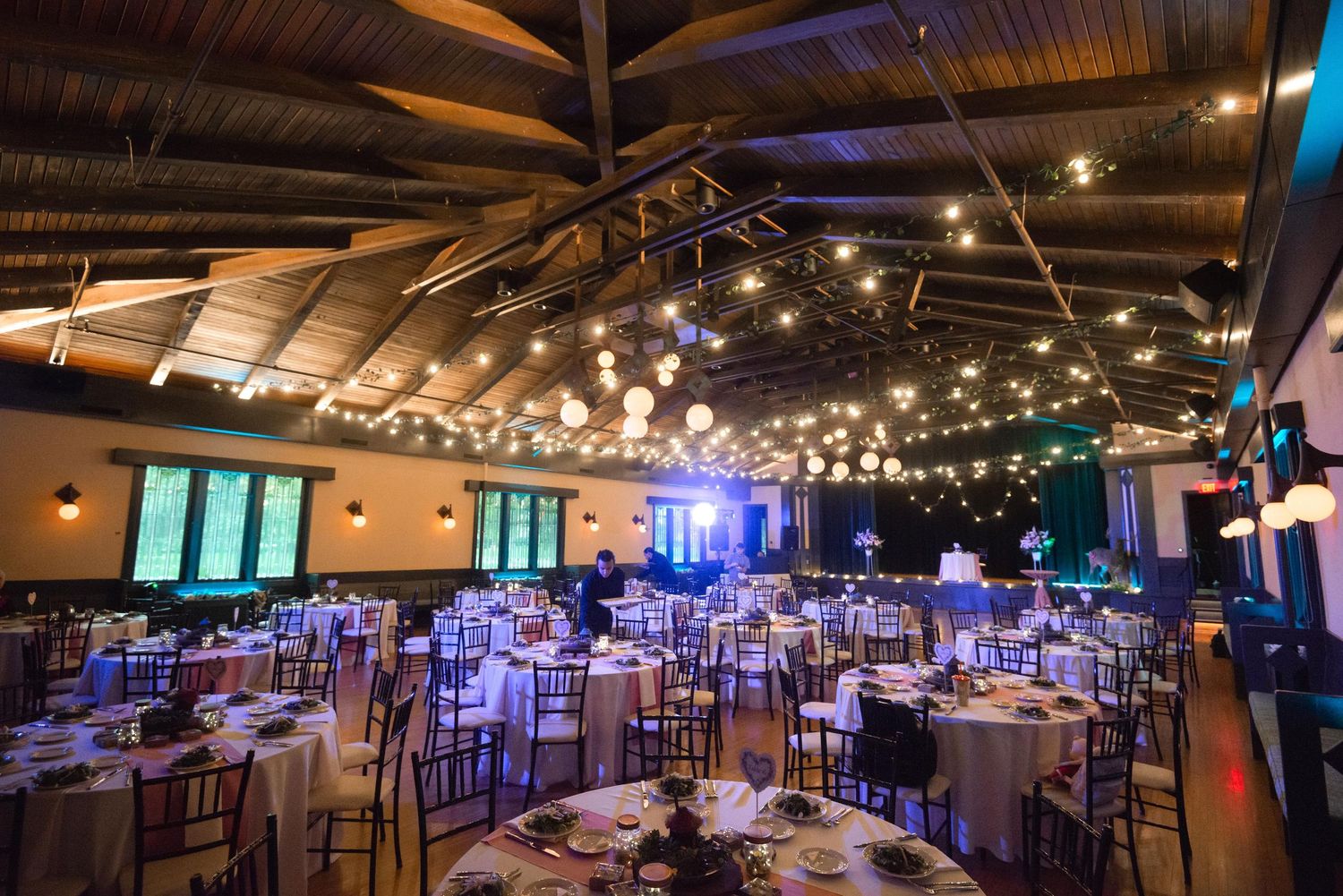Panoramic view of wedding reception hall with elegant lighting and table settings.