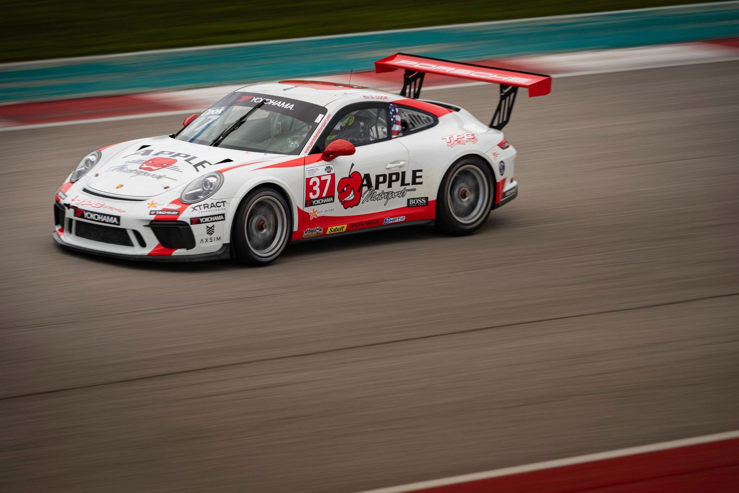 Sports cars race around a curved track during a professional motorsport event.