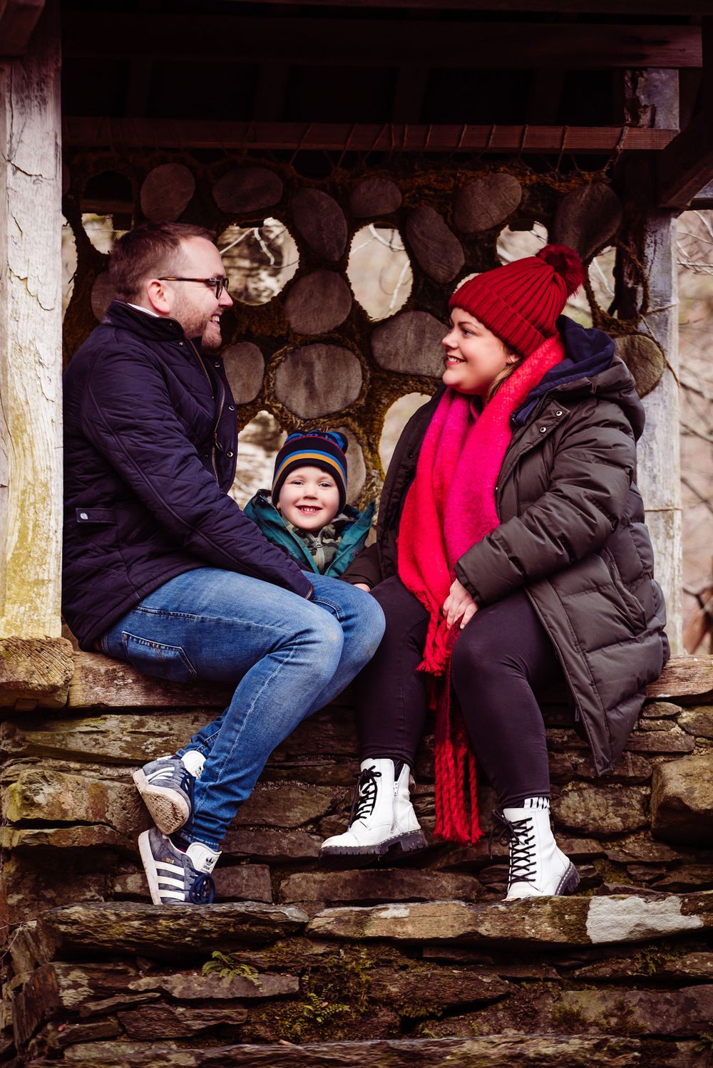 Family sharing a cozy moment together in a rustic wooden shelter during winter.