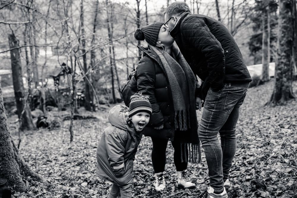 Black and white portrait of family group embracing outdoors in winter clothing.