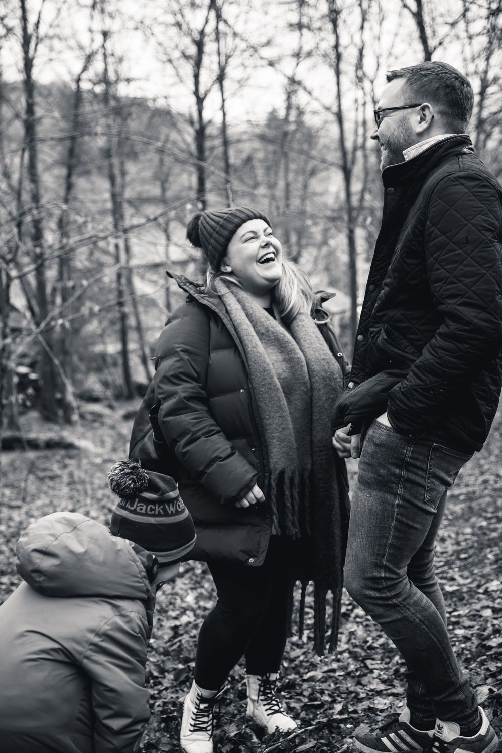Black and white candid photograph of people sharing a laugh in the forest.