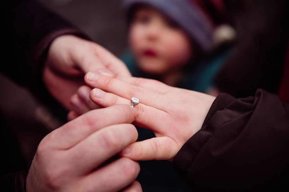 Close-up of hands with an engagement ring in warm lighting.